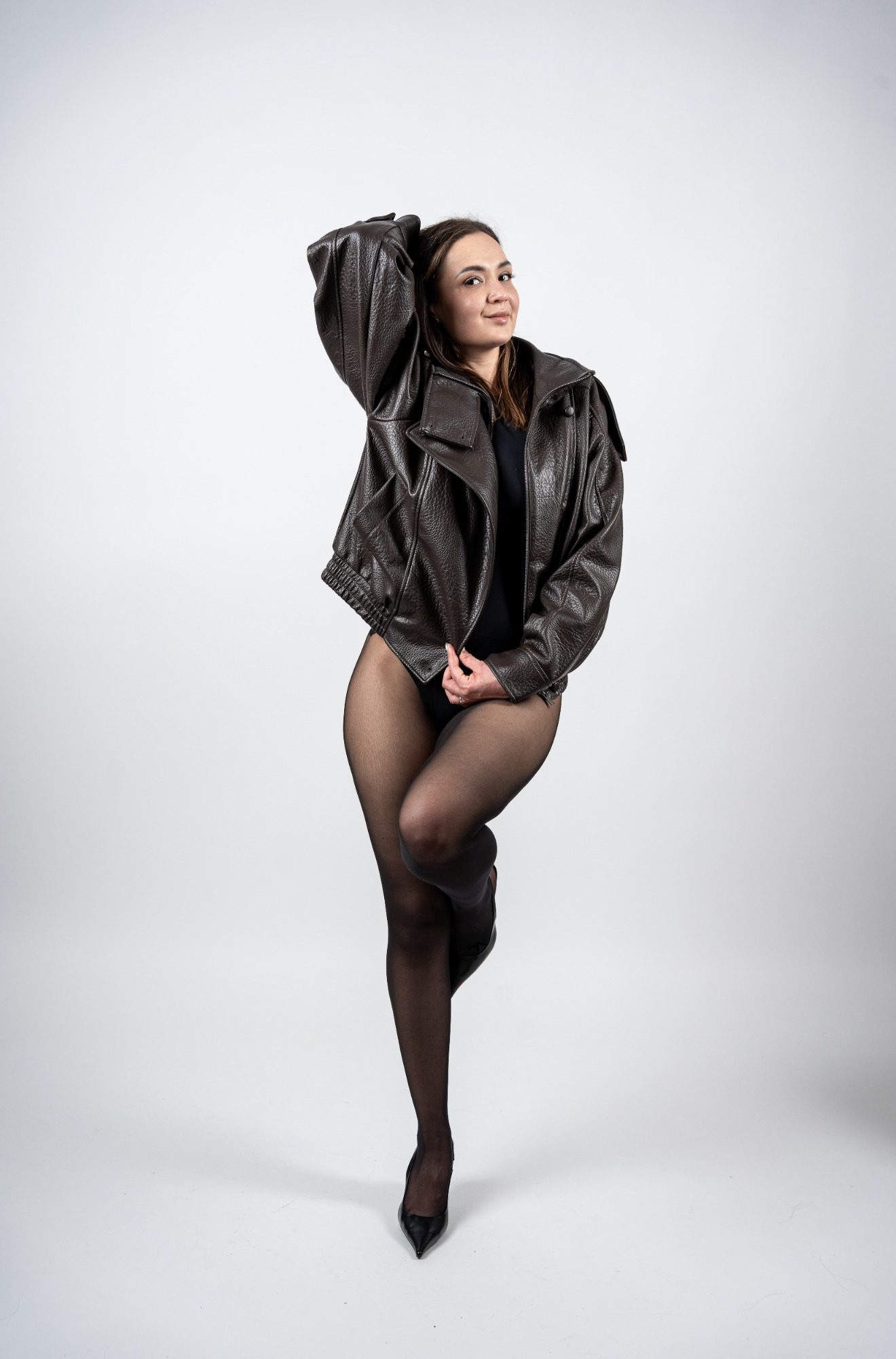 Individuelles Fotoshooting bei AuraMirror Frau in Lederjacke posiert im Fotostudio vor weißem Hintergrund